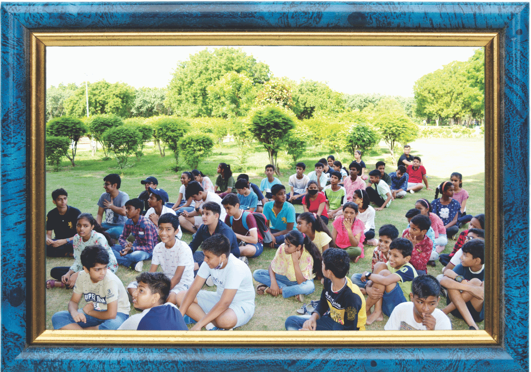 This is the third framed outdoor photo with a large group of students sitting on the grass, seemingly during an event or session.